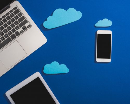 top view of empty paper clouds near laptop, smartphone and digital tablet with blank screen isolated top view of empty paper clouds near laptop, smartphone and digital tablet with blank screen isolated